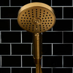 Gold shower head against a black tiled wall