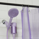 A lilac purple shower head and matching shower attachment hanging from a black rod next to a translucent purple shower curtain in a tiled bathroom.