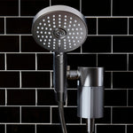 Moonlight Shower head with handheld shower attachment against a black tiled wall